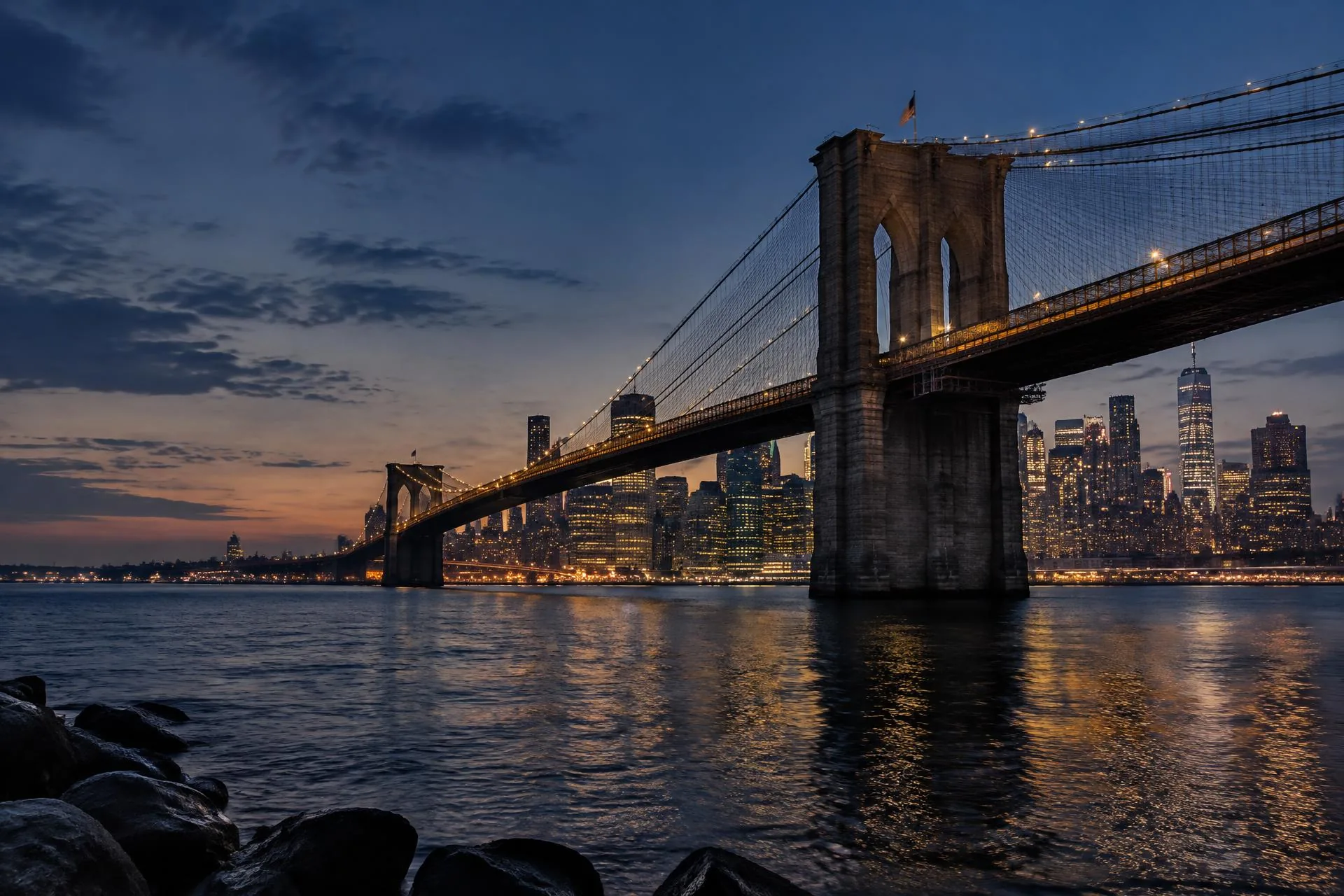 Brooklyn Bridge and the Manhattan skyline at dusk, with city lights glowing